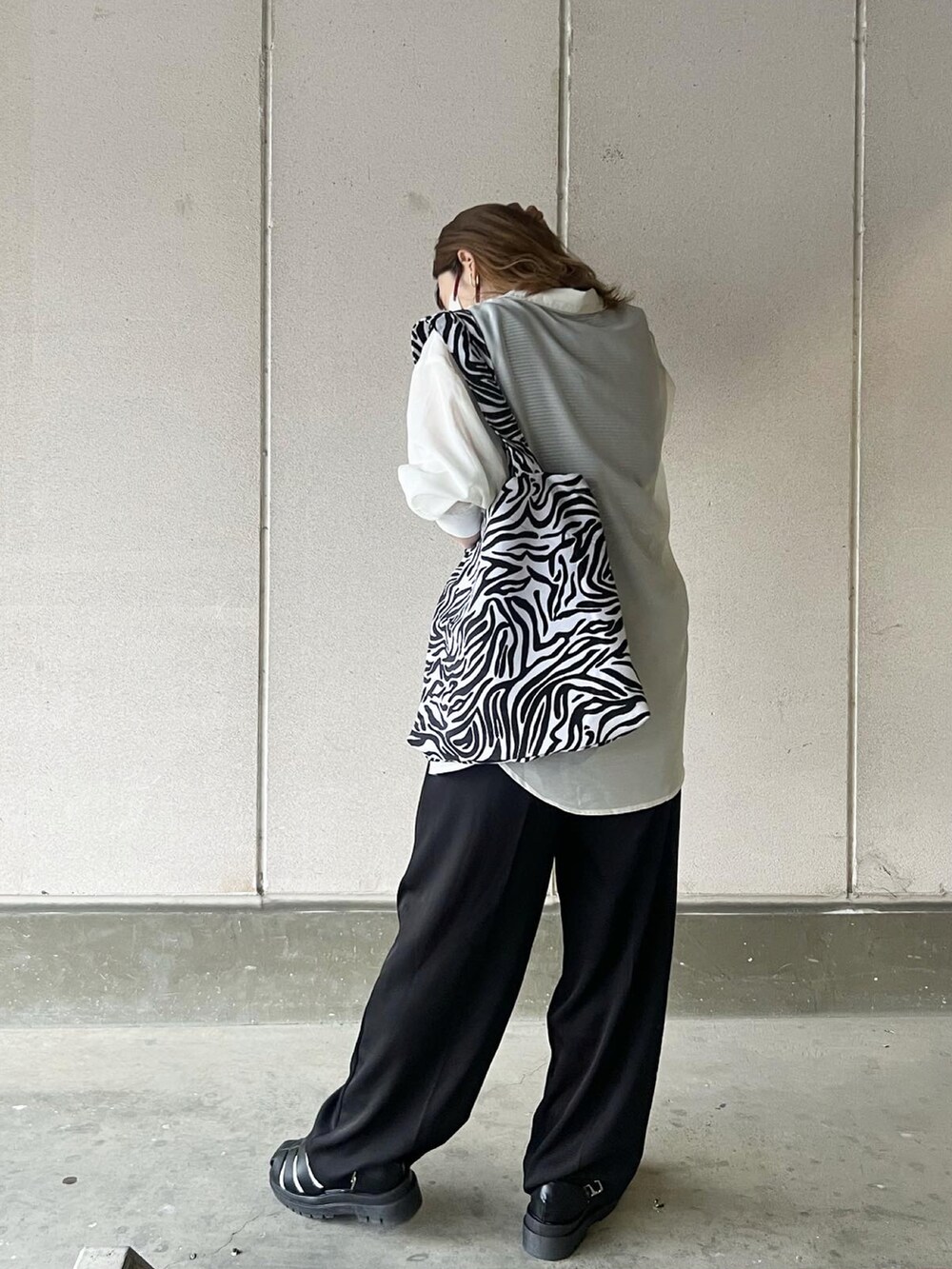 ブラック系のスラックス、その他のトートバッグ、ブラック系のサンダルを着用したレディースの春コーディネートの3枚目の写真