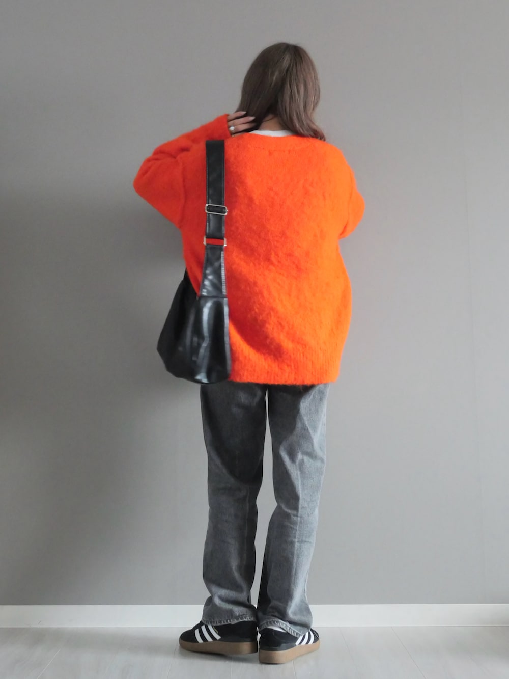 グレー系のスウェット、オレンジ系のカーディガン/ボレロ、ブルー系のデニムパンツを着用したレディースの秋コーディネートの3枚目の写真