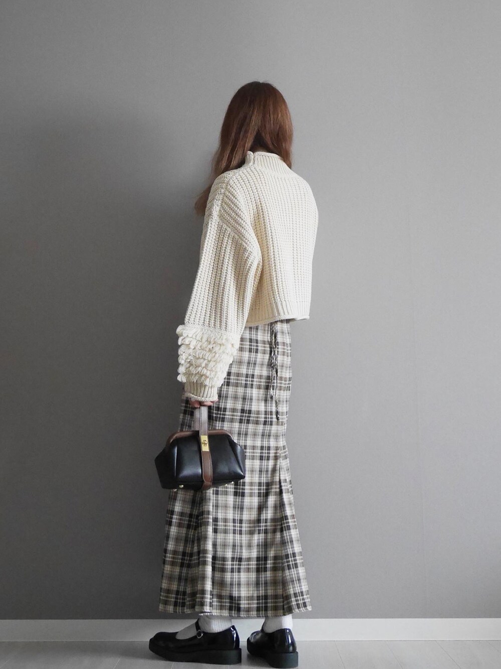 ホワイト系のニット/セーター、ベージュ系のスカート、ブラック系のショルダーバッグを着用したレディースの冬コーディネートの2枚目の写真