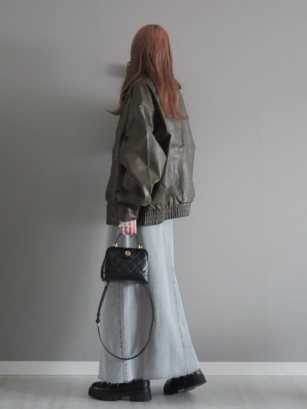 グレー系のデニムスカート、ブラック系のトートバッグ、ブラウン系のブルゾンを着用したレディースの冬コーディネートの4枚目の写真