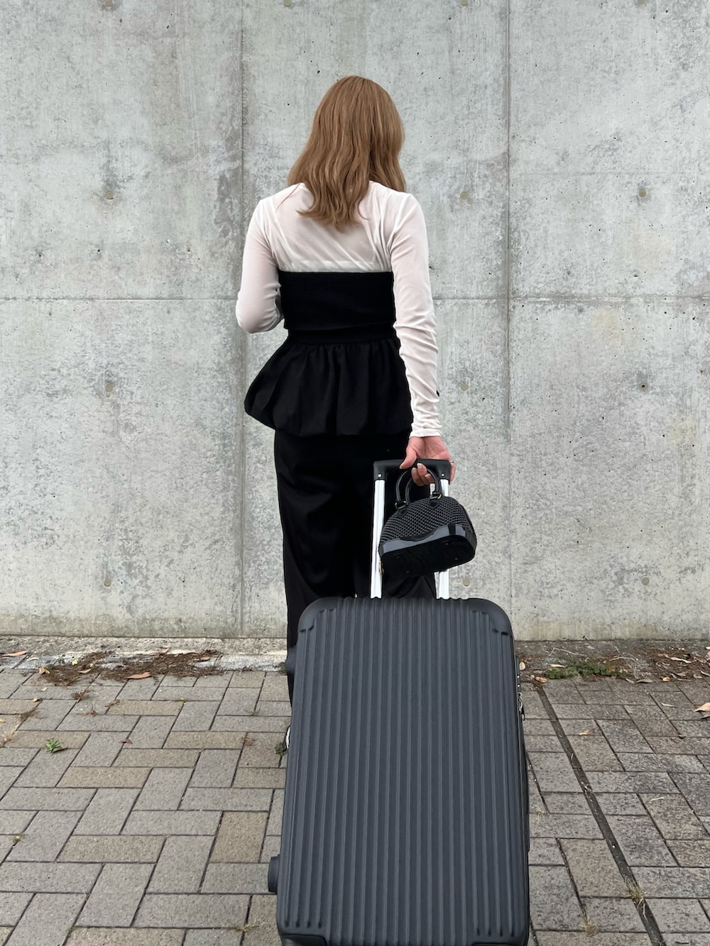 ブラック系のチューブトップ、ホワイト系のTシャツ/カットソー、ブラック系のスラックスを着用したレディースの秋コーディネートの3枚目の写真