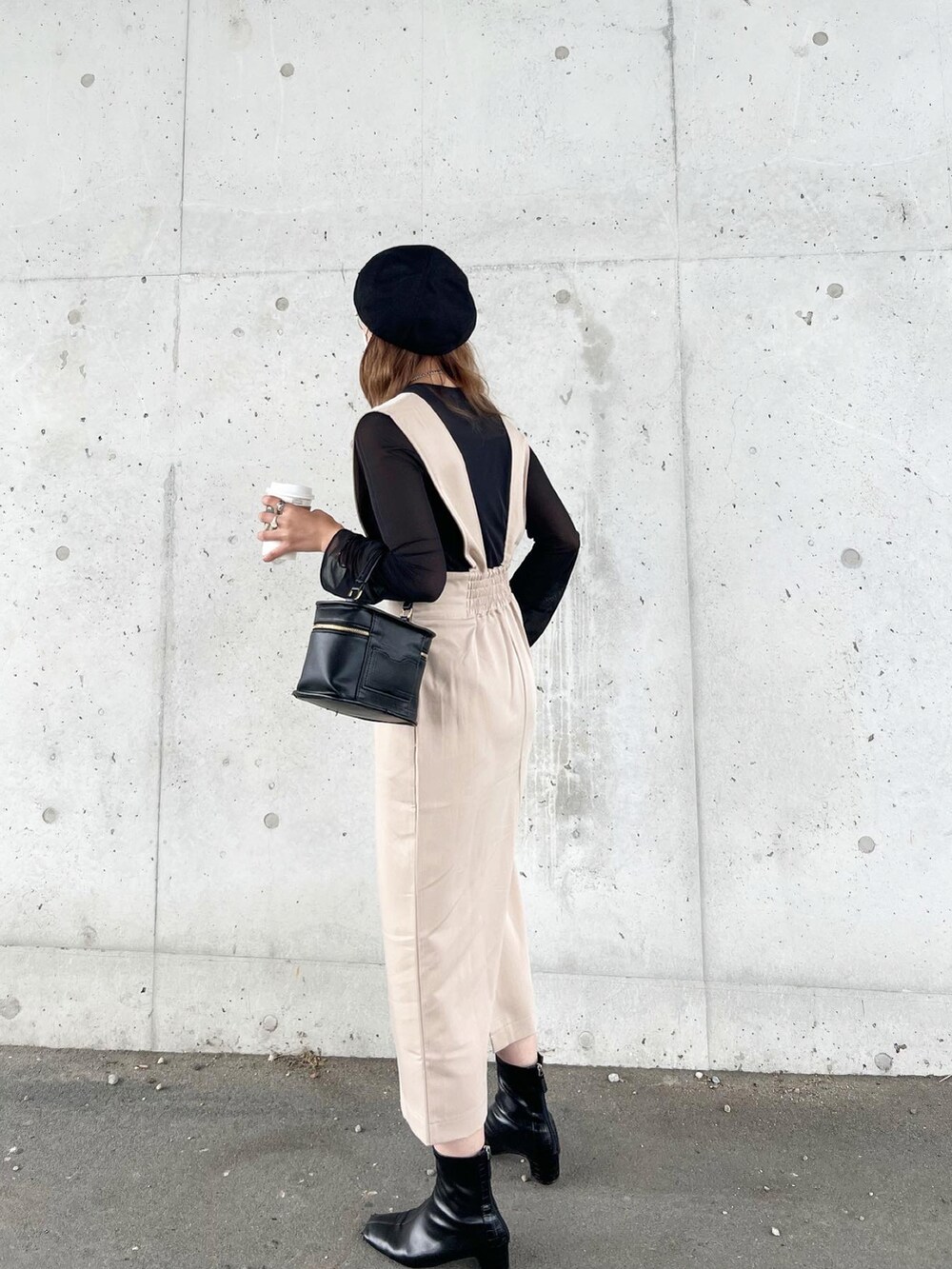 ベージュ系のジャンパースカート、ブラック系のトップス、ブラック系のショルダーバッグを着用したレディースの秋コーディネートの3枚目の写真