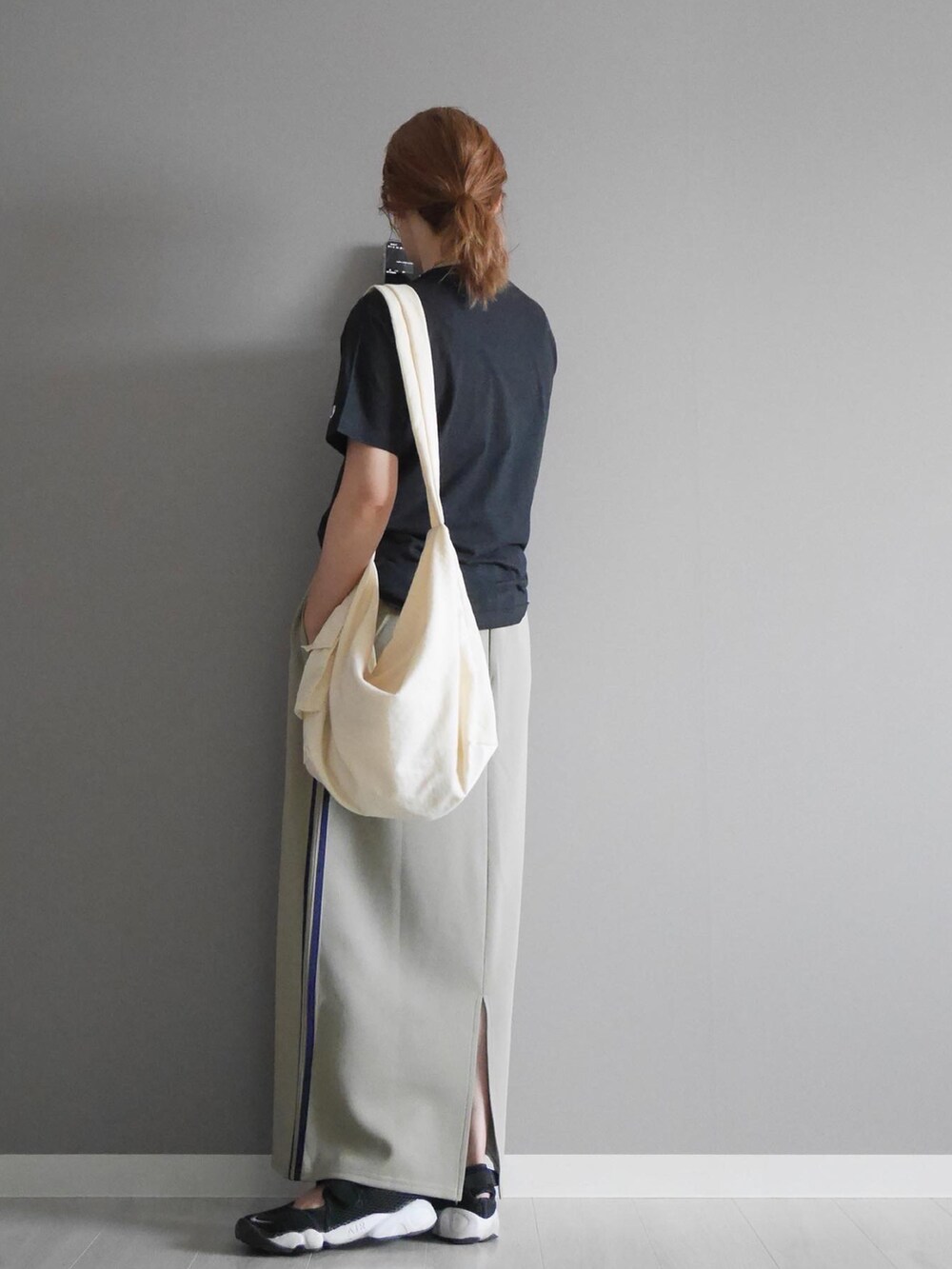 ブラック系のTシャツ/カットソー、ブルー系のスカート、ホワイト系のショルダーバッグを着用したレディースの夏コーディネートの2枚目の写真