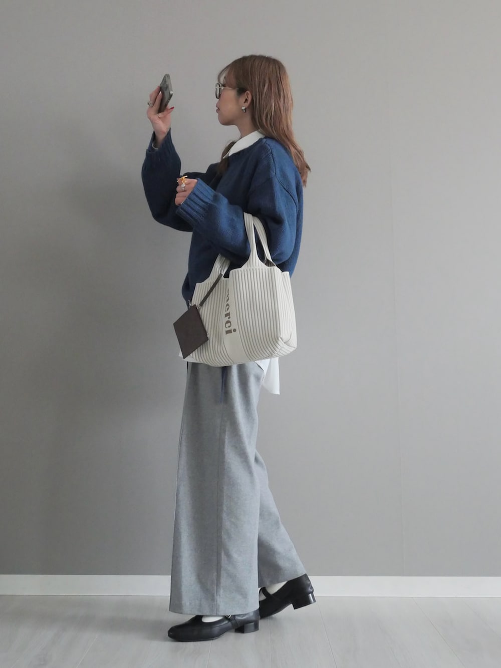 ブルー系のニット/セーター、ホワイト系のシャツ/ブラウス、グレー系のパンツを着用したレディースの冬コーディネートの3枚目の写真