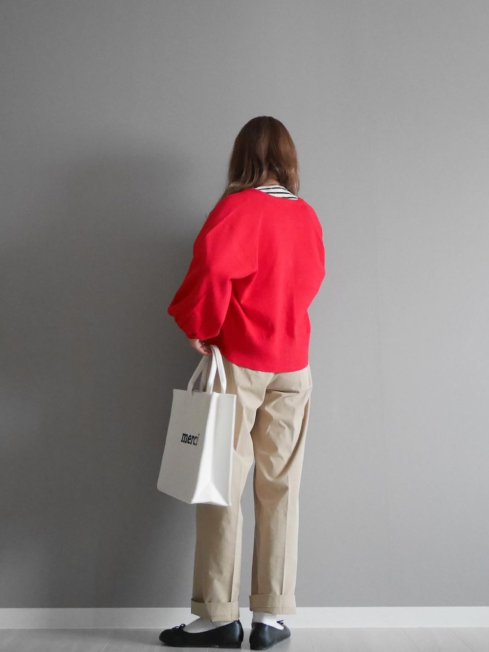 レッド系のカーディガン/ボレロ、ブラック系のTシャツ/カットソー、ベージュ系のチノパンツを着用したレディースの秋コーディネートの2枚目の写真