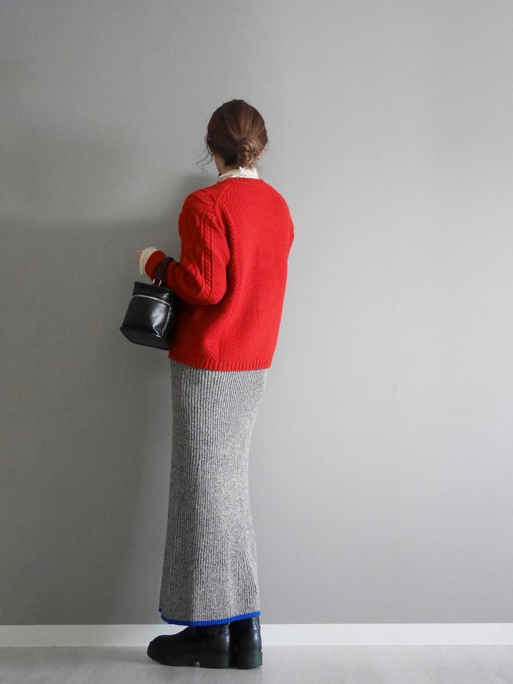 レッド系のニット/セーター、グレー系のスカート、ブラック系のショルダーバッグを着用したレディースの秋コーディネートの2枚目の写真