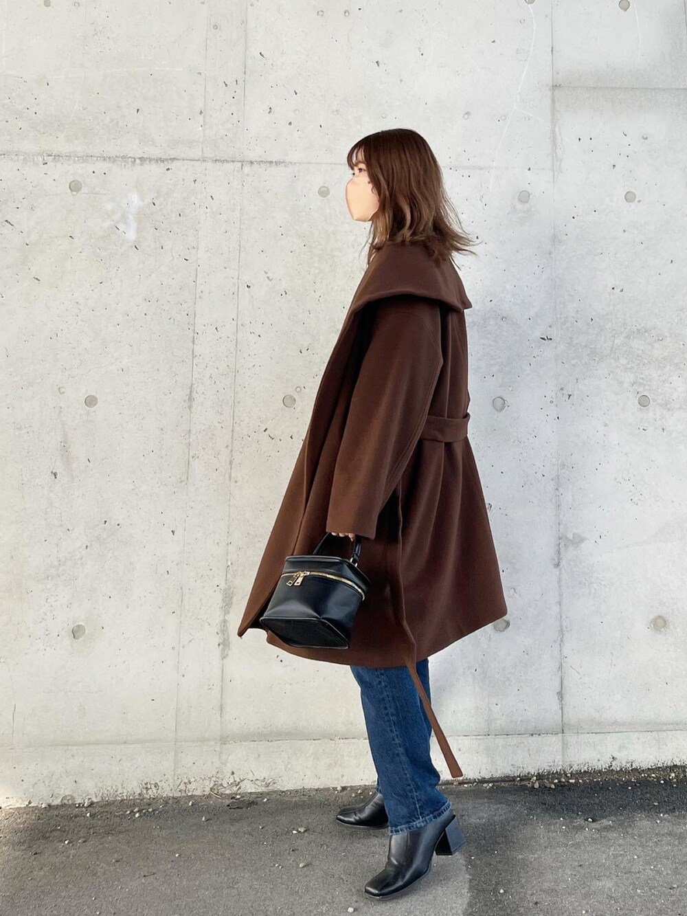 ブラウン系のその他アウター、ブラック系のニット/セーター、ブルー系のデニムパンツを着用したレディースの冬コーディネートの2枚目の写真