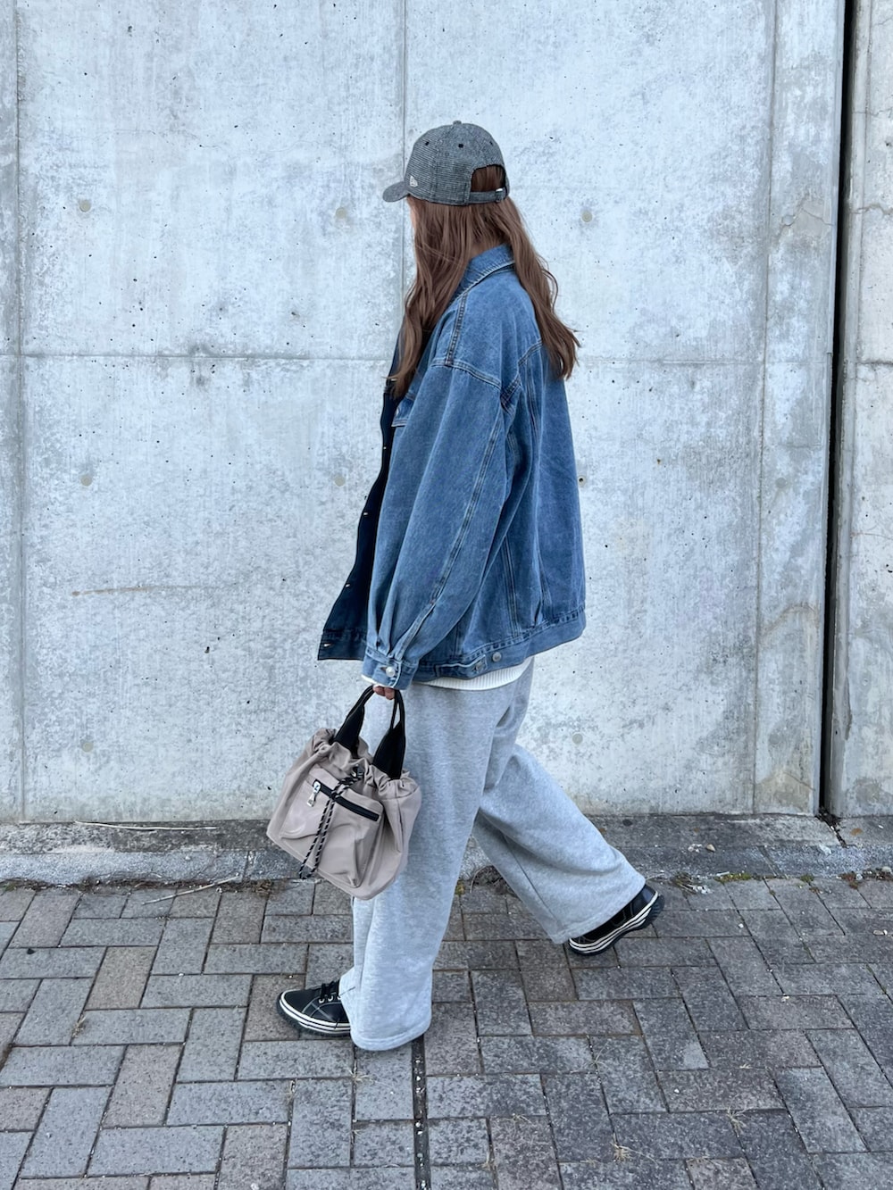 ブルー系のデニムジャケット、ホワイト系のニット/セーター、グレー系のスウェットパンツを着用したレディースの春コーディネートの2枚目の写真