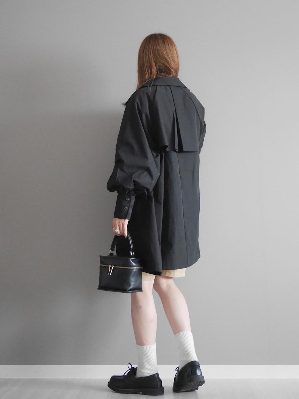 ブラック系のトレンチコート、ホワイト系のシャツ/ブラウス、レッド系のカーディガン/ボレロを着用したレディースの秋コーディネートの2枚目の写真