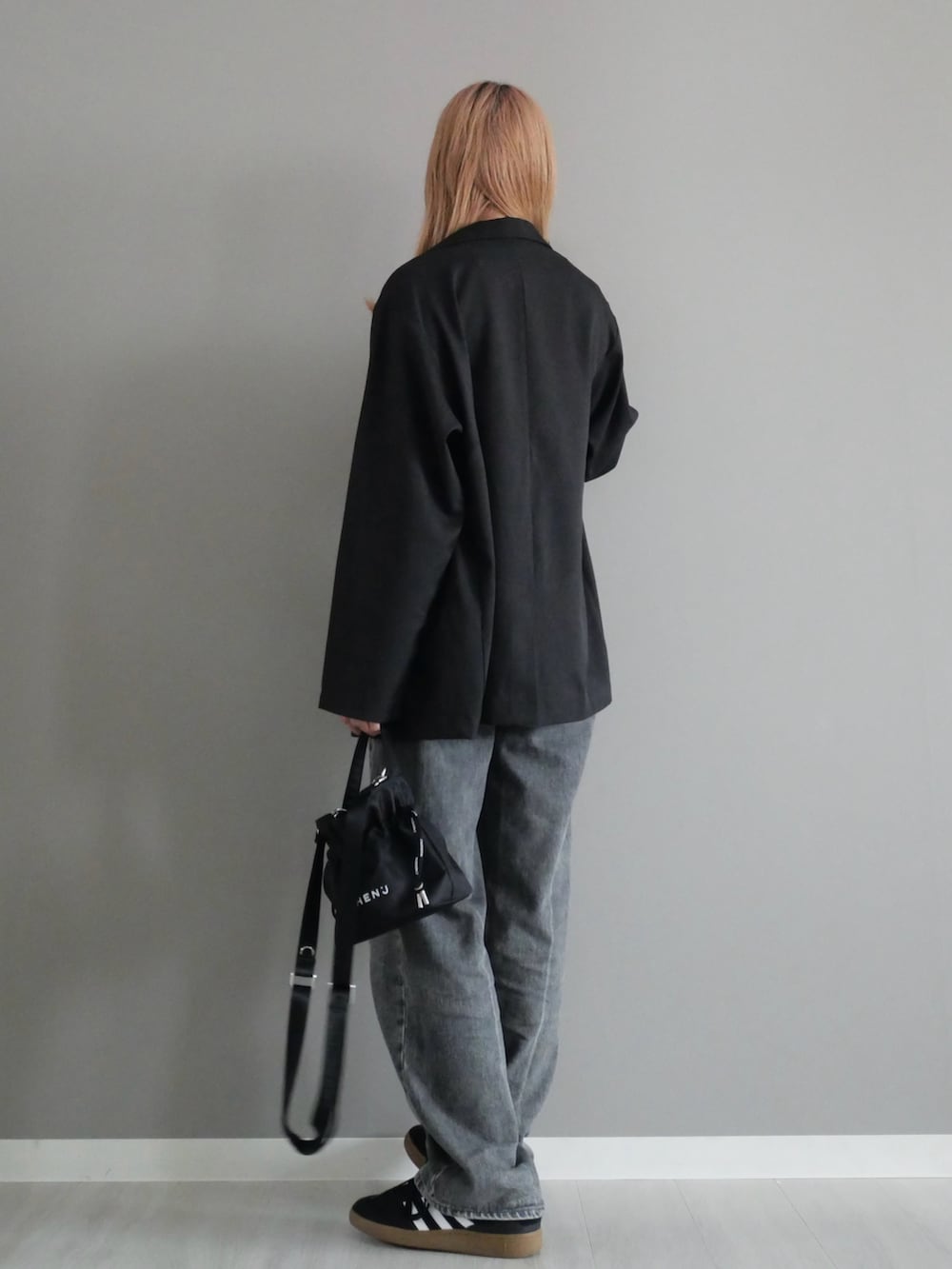 ブラック系のテーラードジャケット、グレー系のデニムパンツ、ブラック系のバッグを着用したレディースの夏コーディネートの3枚目の写真