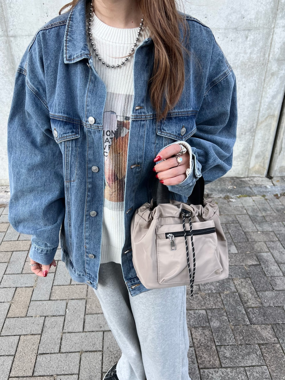 ブルー系のデニムジャケット、ホワイト系のニット/セーター、グレー系のスウェットパンツを着用したレディースの春コーディネートの3枚目の写真