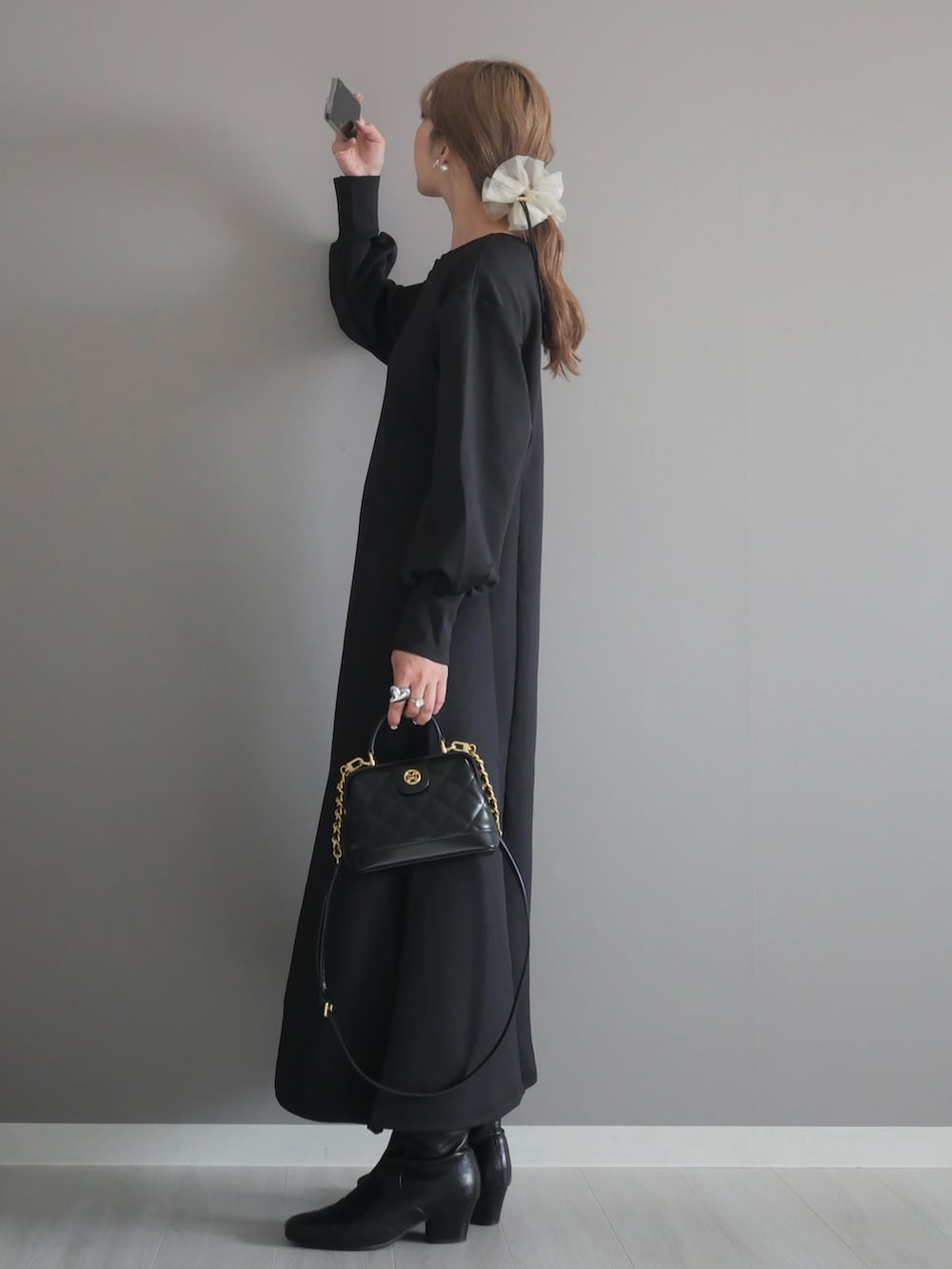 ブラック系のトートバッグ、ブラック系のワンピース、ブラック系のブーツを着用したレディースの秋コーディネートの4枚目の写真