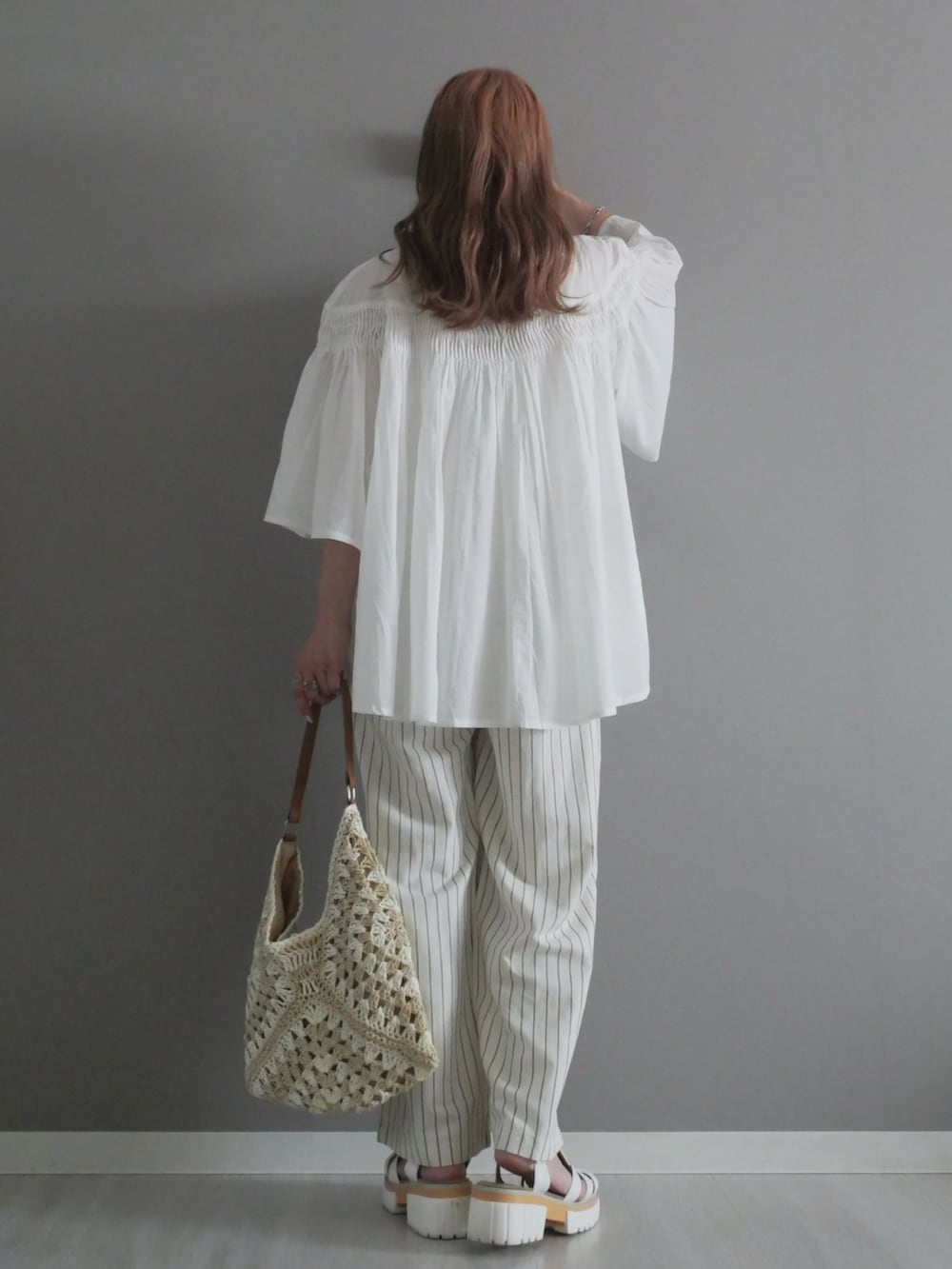 ホワイト系のパンツ、ベージュ系のかごバッグ、ホワイト系のサンダルを着用したレディースの夏コーディネートの4枚目の写真