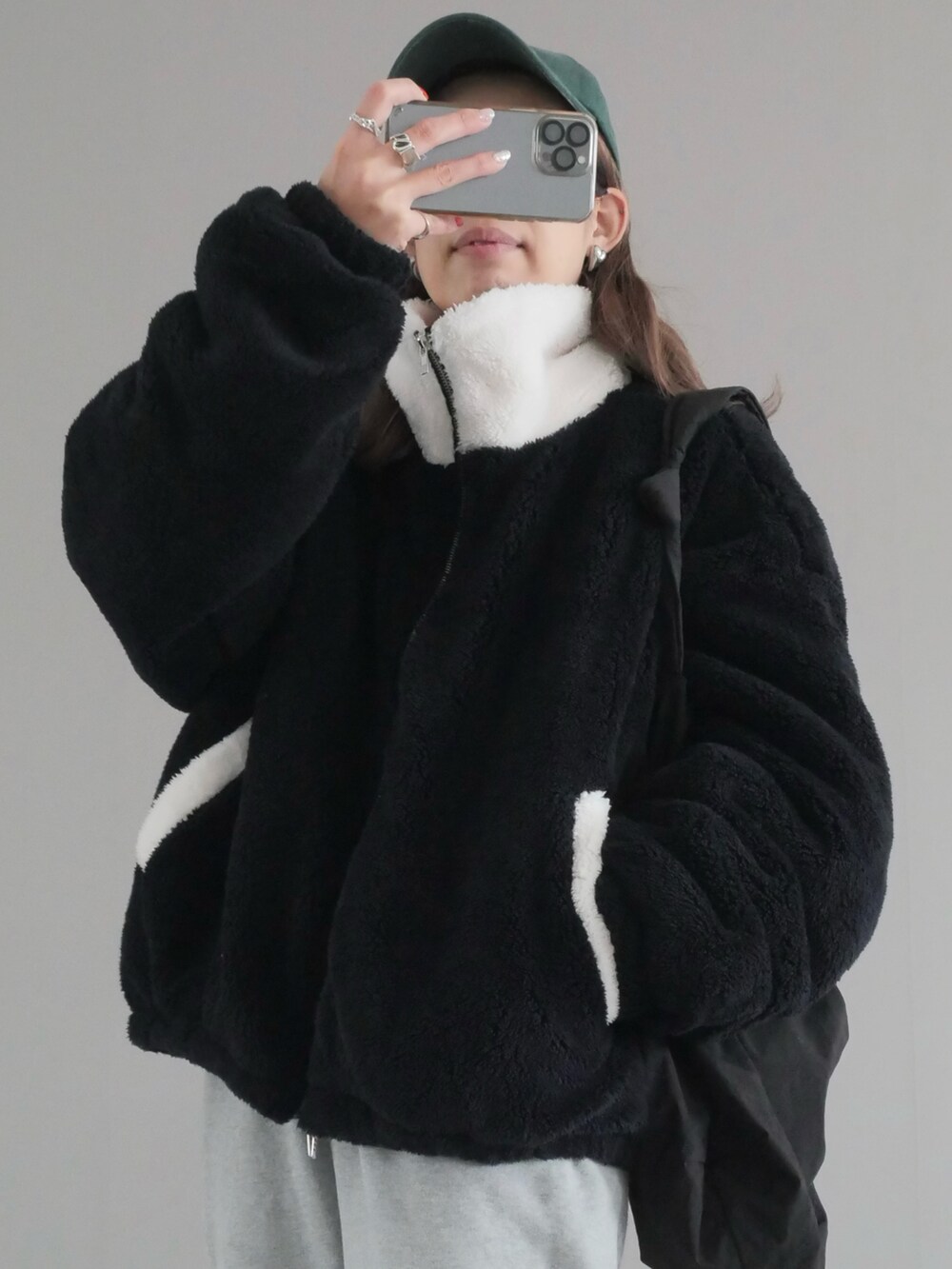 ブラック系のブルゾン、ホワイト系のパンツ、ブラック系のブーツを着用したレディースの冬コーディネートの2枚目の写真