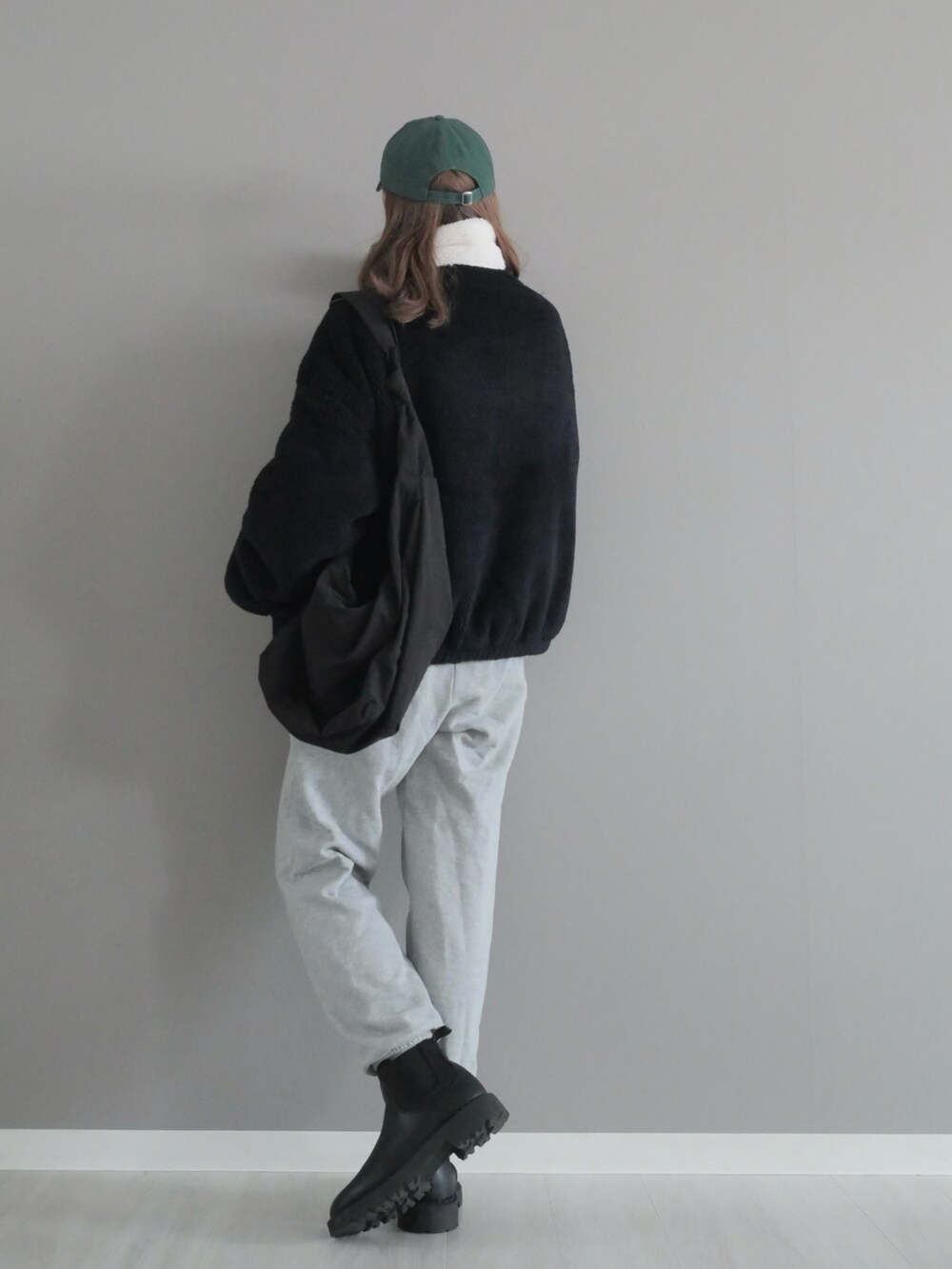 ブラック系のブルゾン、ホワイト系のパンツ、ブラック系のブーツを着用したレディースの冬コーディネートの3枚目の写真