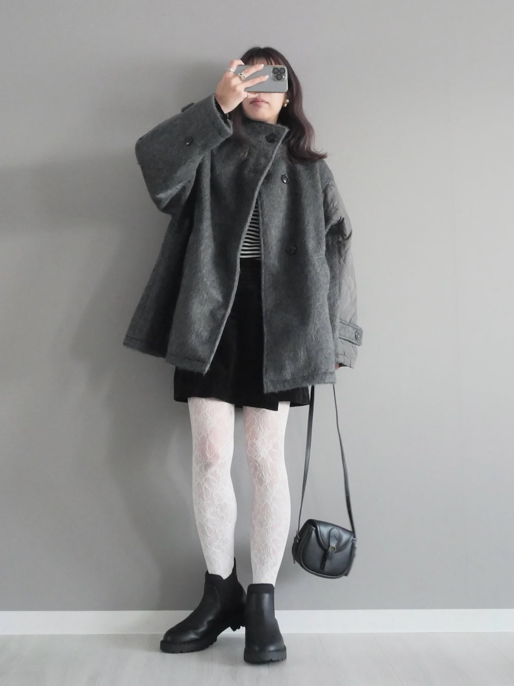 グレー系のステンカラーコート、ブラック系のパンツ、ブラック系のブーツを着用したレディースの秋コーディネートの3枚目の写真