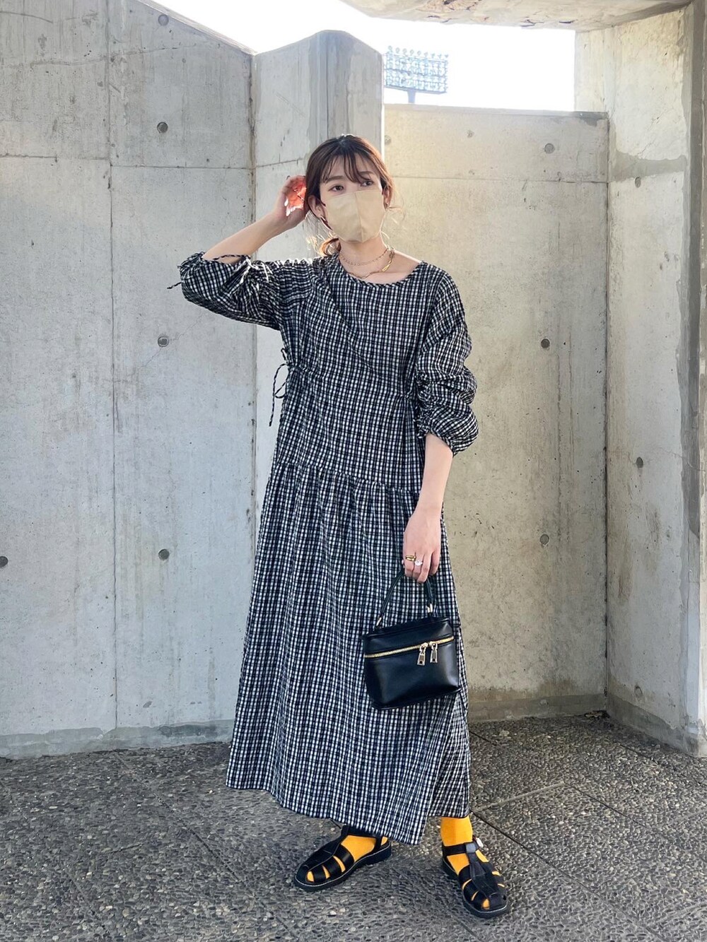 ブラック系のワンピース、ブラック系のショルダーバッグ、ブラック系のサンダルを着用したレディースの春コーディネートの2枚目の写真