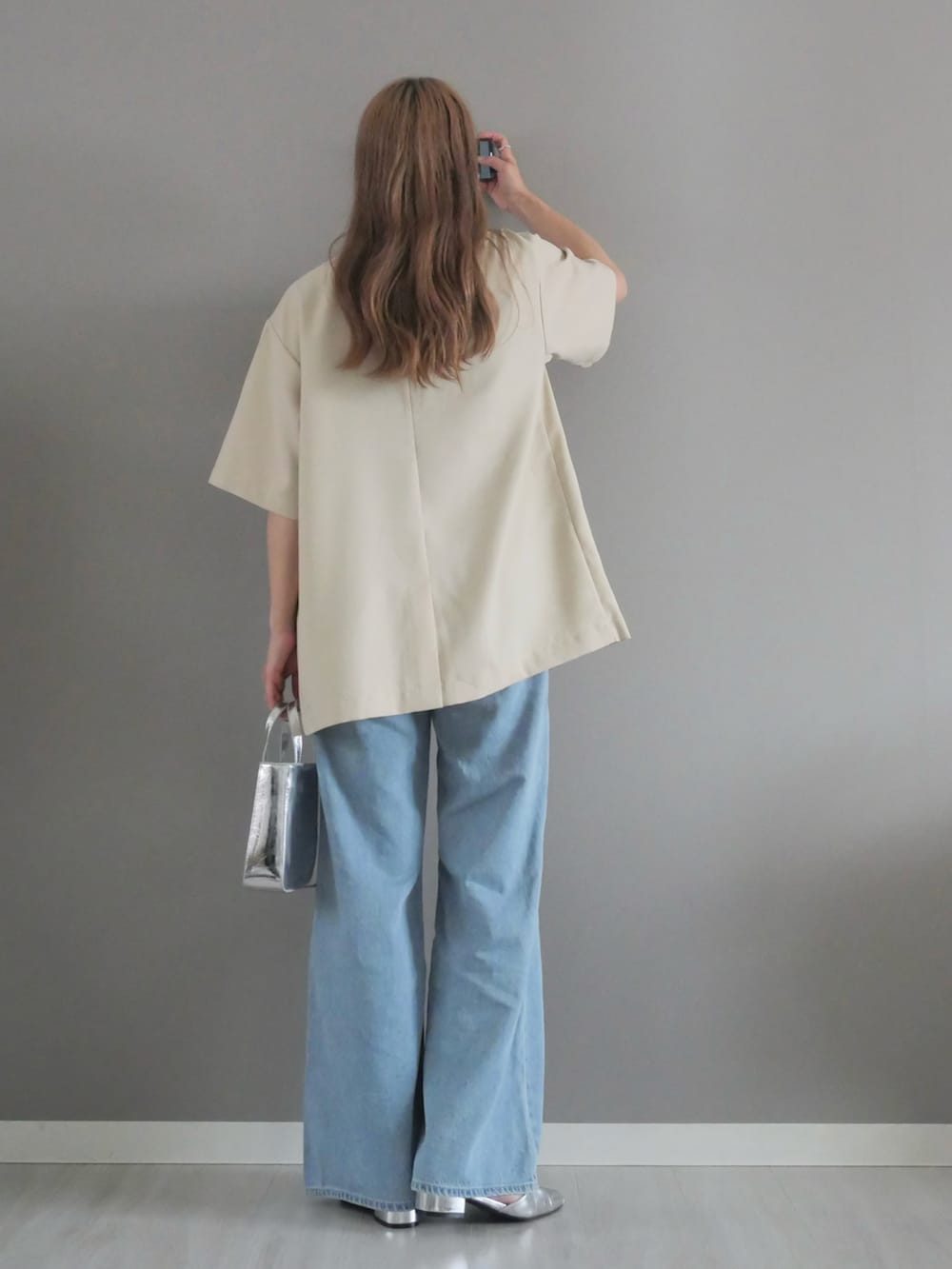 ホワイト系のテーラードジャケット、ブラック系のキャミソール、シルバー系のハンドバッグを着用したレディースの夏コーディネートの3枚目の写真