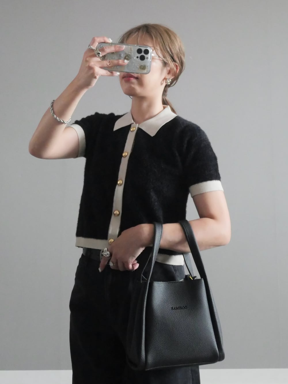 ブラック系のハンドバッグ、ブラック系のニット/セーター、シルバー系のリングを着用したレディースの秋コーディネートの3枚目の写真