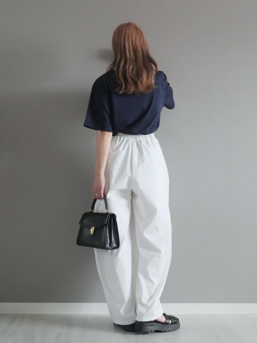 ブルー系のTシャツ/カットソー、ブラック系のトートバッグ、ホワイト系のチノパンツを着用したレディースの夏コーディネートの4枚目の写真