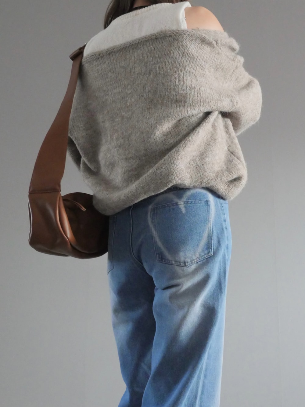 ブルー系のデニムパンツ、ベージュ系のニット/セーター、イエロー系のショルダーバッグを着用したレディースの冬コーディネートの2枚目の写真