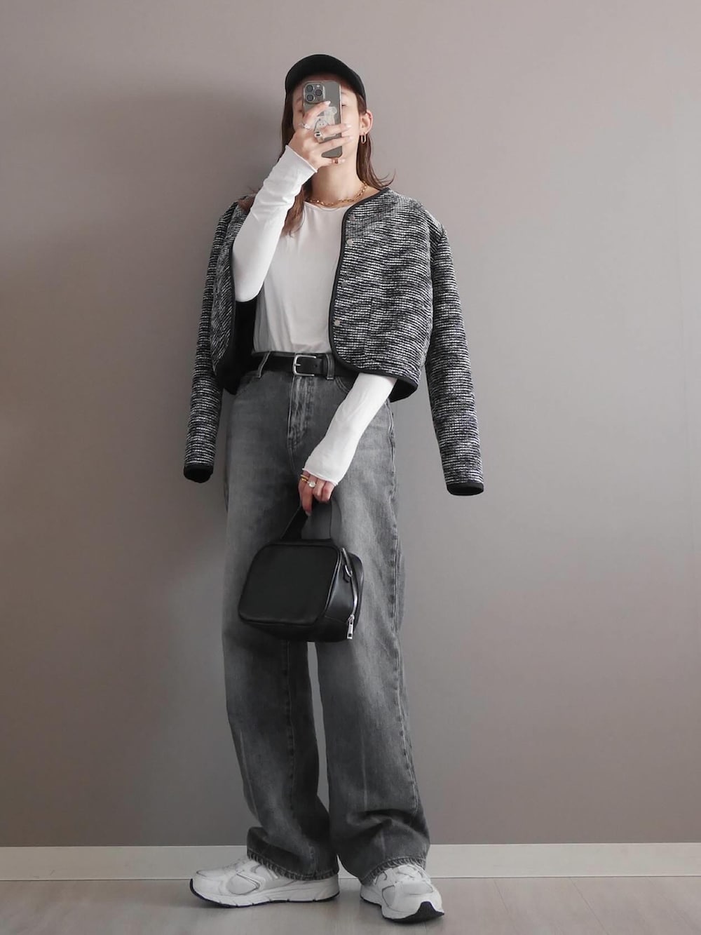 ブラック系のノーカラージャケット、ホワイト系のTシャツ/カットソー、グレー系のデニムパンツを着用したレディースの冬コーディネートの2枚目の写真