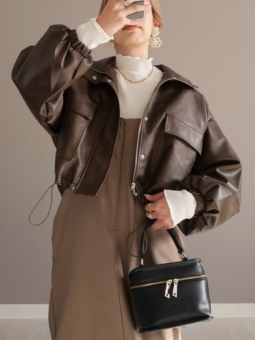 ブラウン系のブルゾン、ホワイト系のTシャツ/カットソー、ベージュ系のワンピースを着用したレディースの秋コーディネートの2枚目の写真