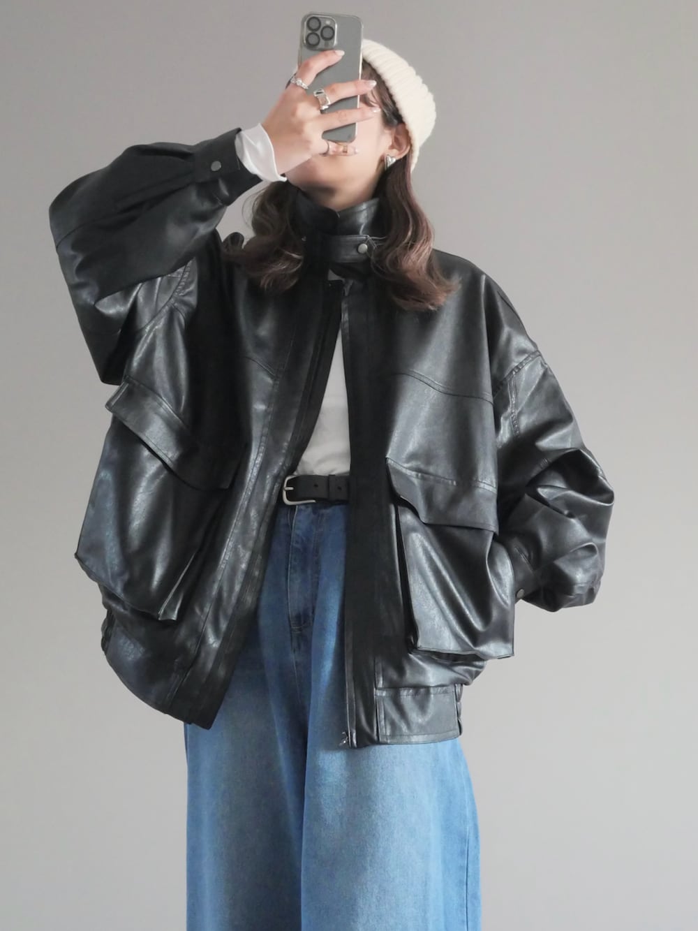 ブラック系のブルゾン、ホワイト系のTシャツ/カットソー、ブルー系のデニムパンツを着用したレディースの冬コーディネートの2枚目の写真