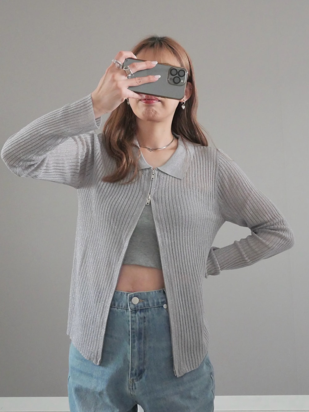 グレー系のカーディガン/ボレロ、ブルー系のデニムパンツ、ホワイト系のハンドバッグを着用したレディースの春コーディネートの2枚目の写真