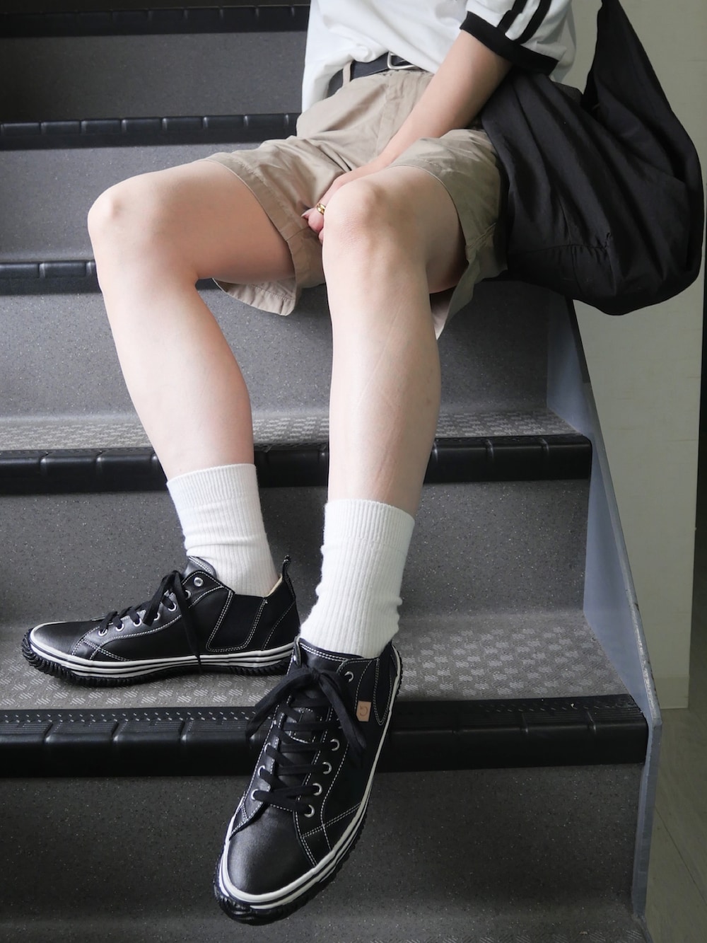 ブラック系のスニーカー、ホワイト系のTシャツ/カットソー、ベージュ系のパンツを着用したレディースの春コーディネートの5枚目の写真