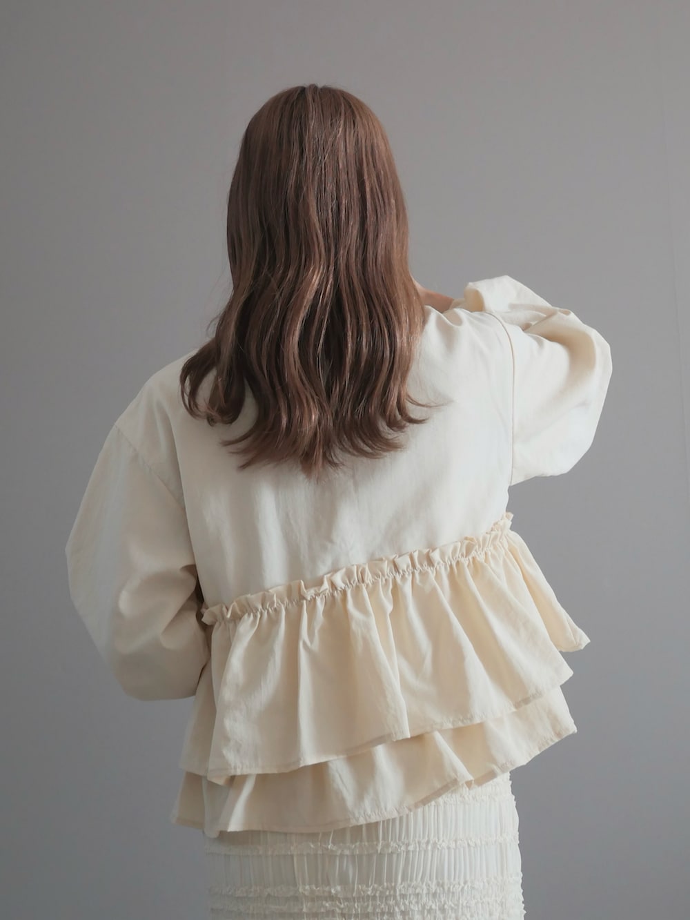 ホワイト系のノーカラージャケット、ホワイト系のスカート、ホワイト系のハンドバッグを着用したレディースの春コーディネートの3枚目の写真