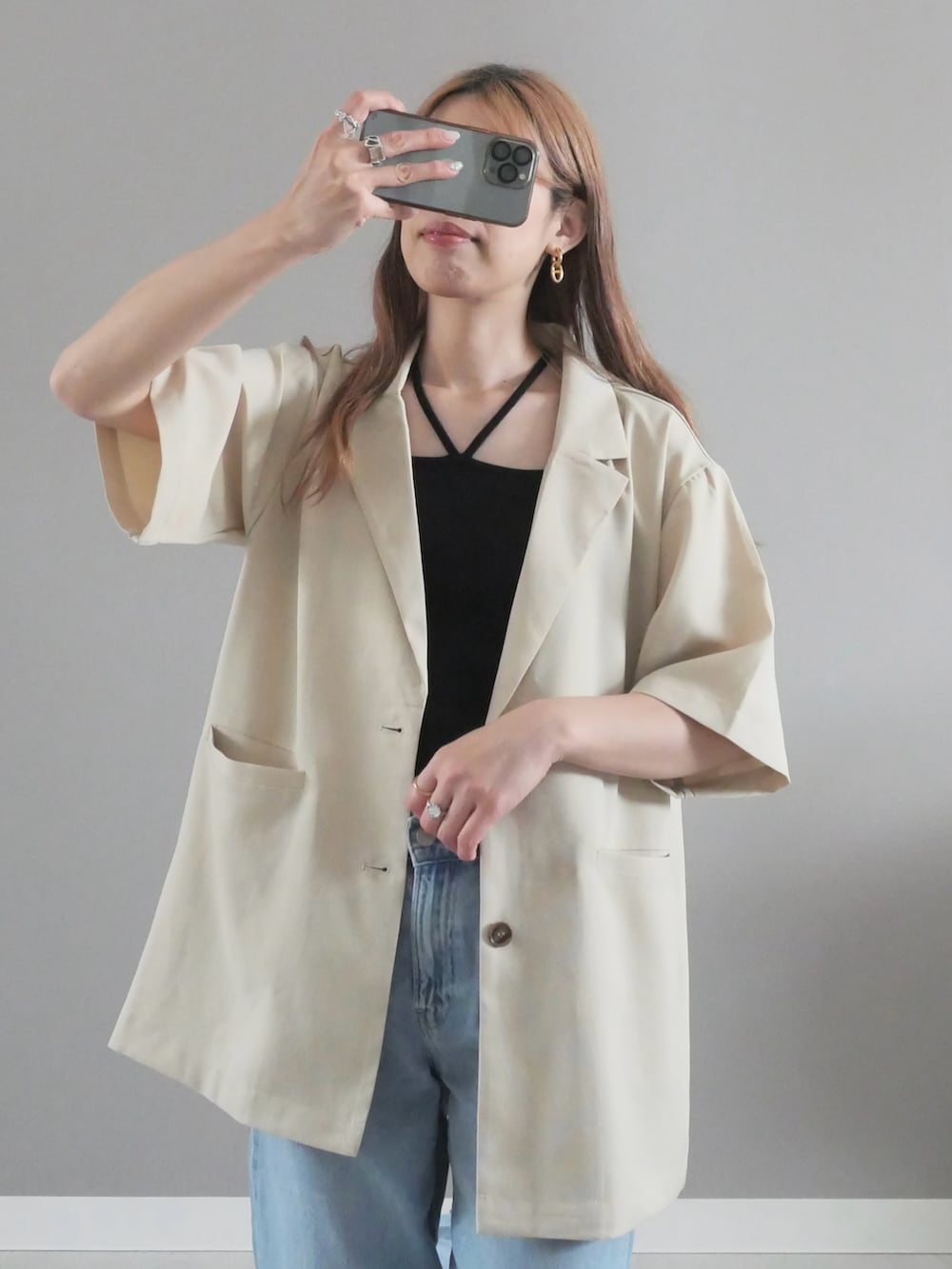 ホワイト系のテーラードジャケット、ブラック系のキャミソール、シルバー系のハンドバッグを着用したレディースの夏コーディネートの2枚目の写真