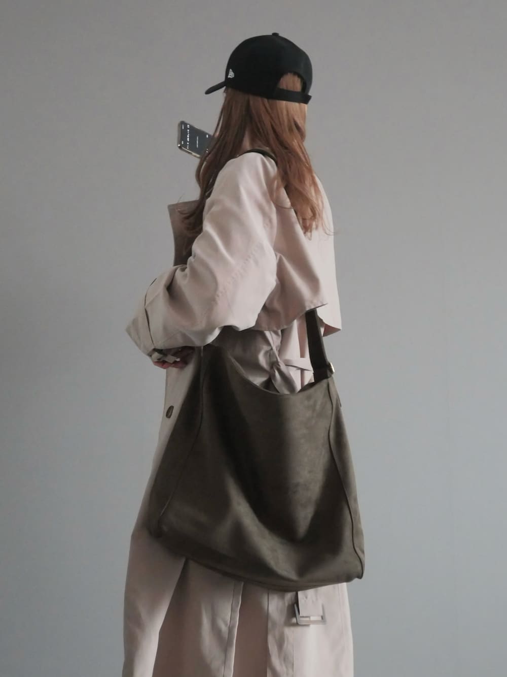 ベージュ系のトレンチコート、グリーン系のショルダーバッグ、ブラック系のスリッポンを着用したレディースの春コーディネートの3枚目の写真