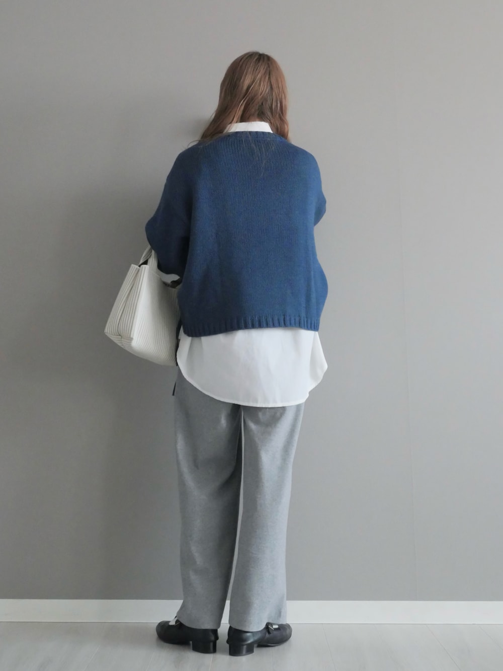 ブルー系のニット/セーター、ホワイト系のシャツ/ブラウス、グレー系のパンツを着用したレディースの冬コーディネートの4枚目の写真