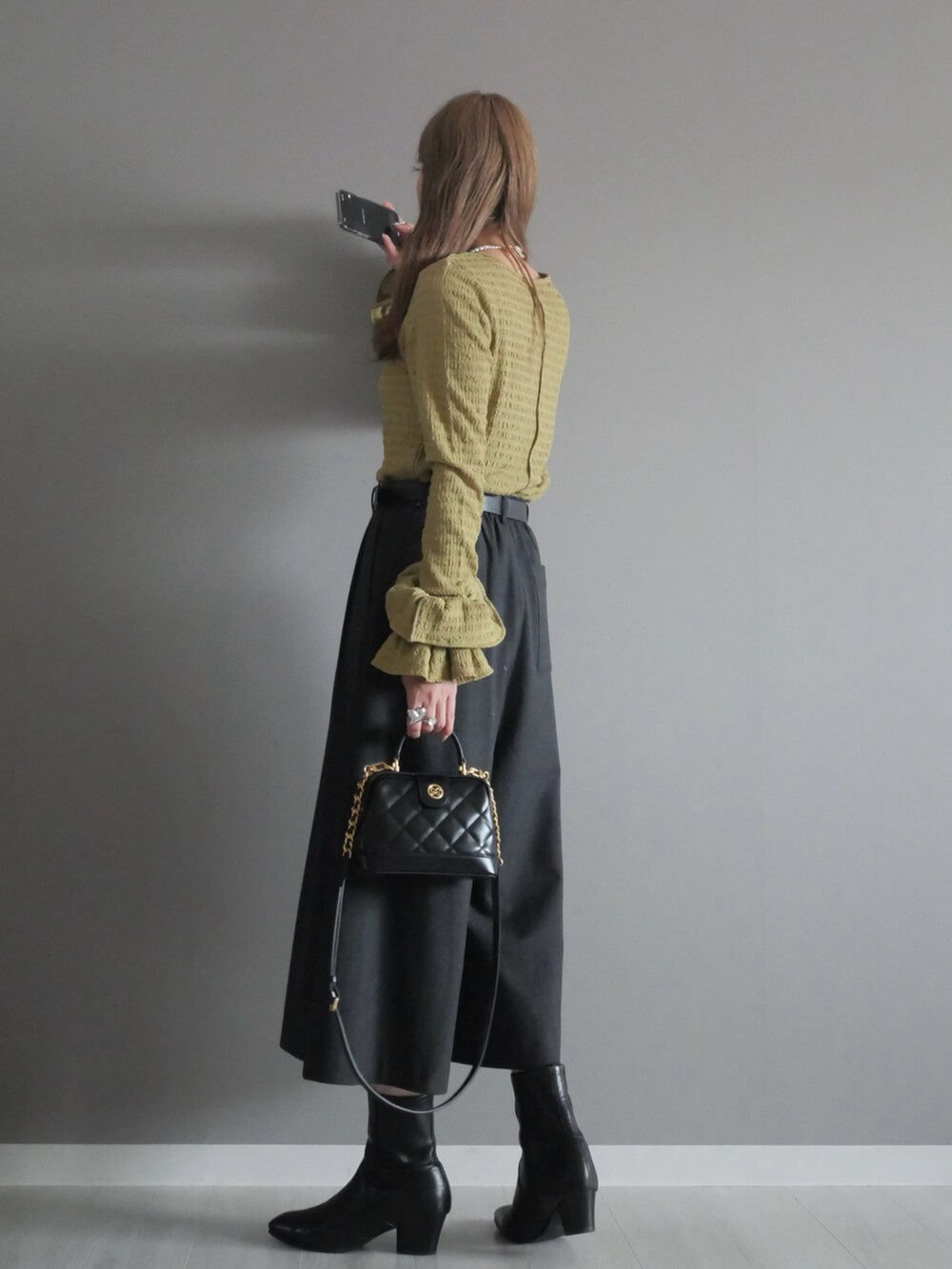 ブラック系のトートバッグ、グリーン系のTシャツ/カットソー、ブラック系のブーツを着用したレディースの秋コーディネートの5枚目の写真