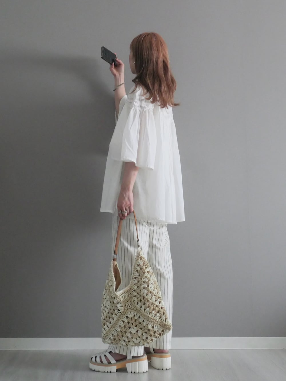 ホワイト系のパンツ、ベージュ系のかごバッグ、ホワイト系のサンダルを着用したレディースの夏コーディネートの3枚目の写真