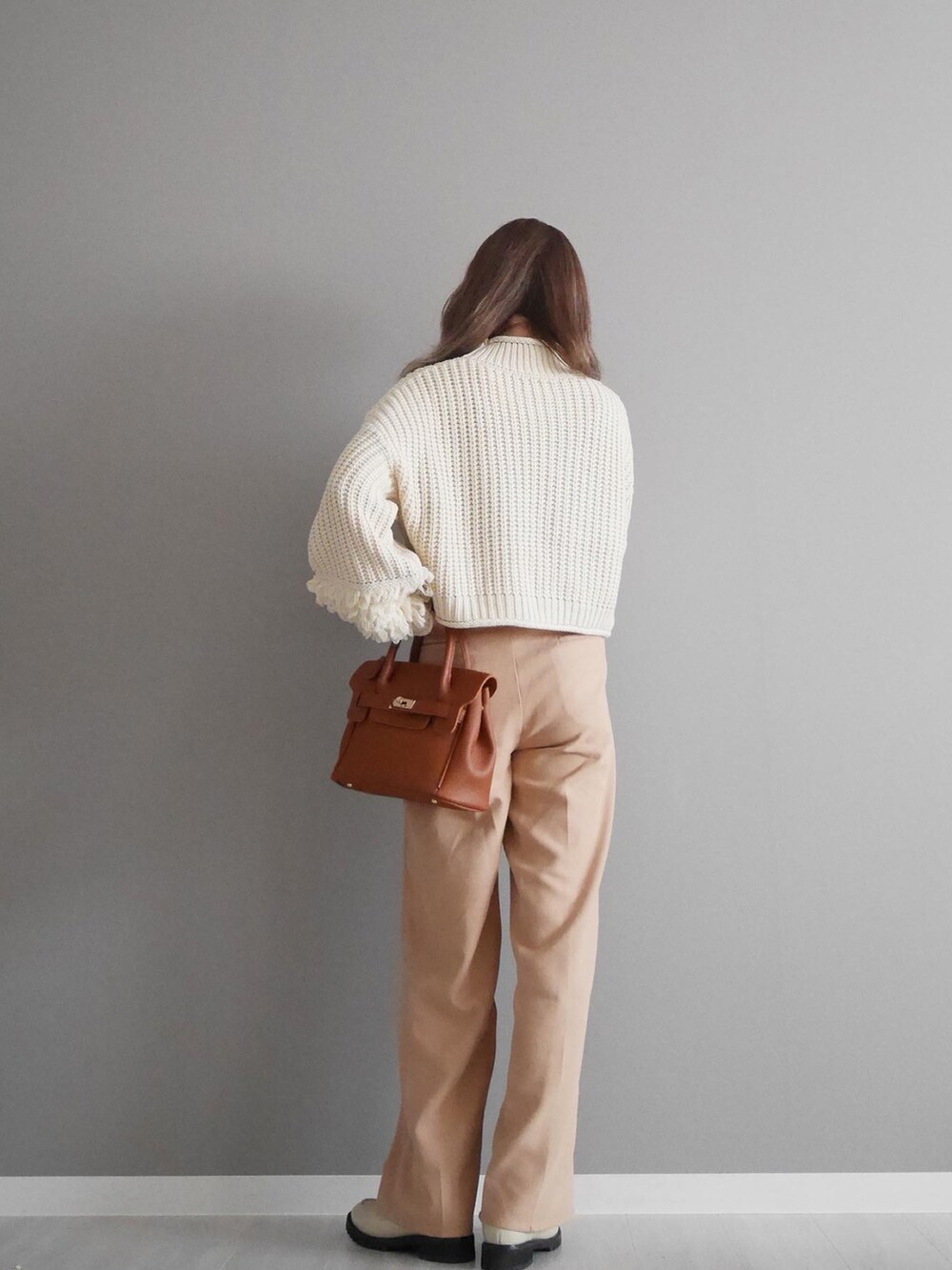 ホワイト系のニット/セーター、ベージュ系のスラックス、イエロー系のハンドバッグを着用したレディースの秋コーディネートの2枚目の写真