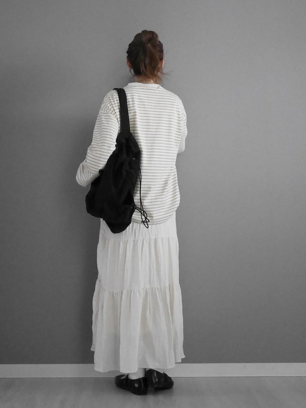 ベージュ系のTシャツ/カットソー、ホワイト系のスカート、ブラック系のショルダーバッグを着用したレディースの冬コーディネートの3枚目の写真