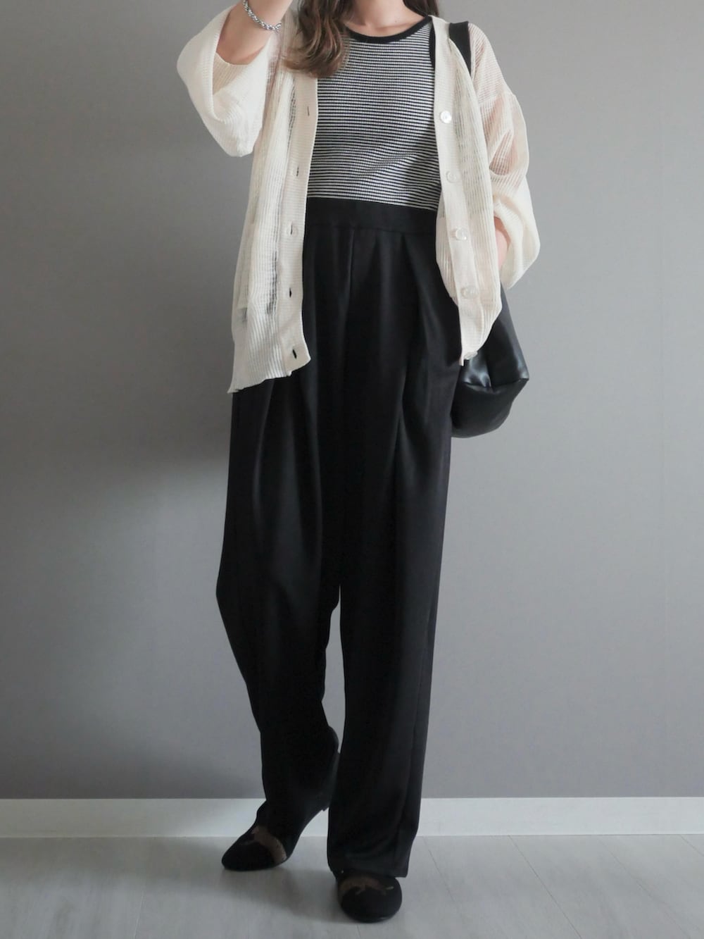 ホワイト系のカーディガン/ボレロ、ブラック系のタンクトップ、ブラック系のスラックスを着用したレディースの秋コーディネートの2枚目の写真