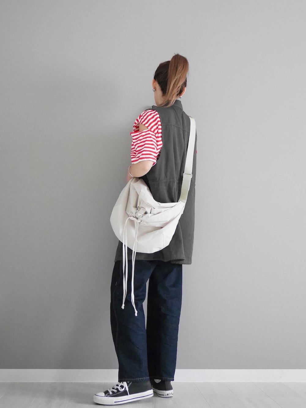 レッド系のTシャツ/カットソー、グレー系のベスト、ブルー系のデニムパンツを着用したレディースの秋コーディネートの2枚目の写真