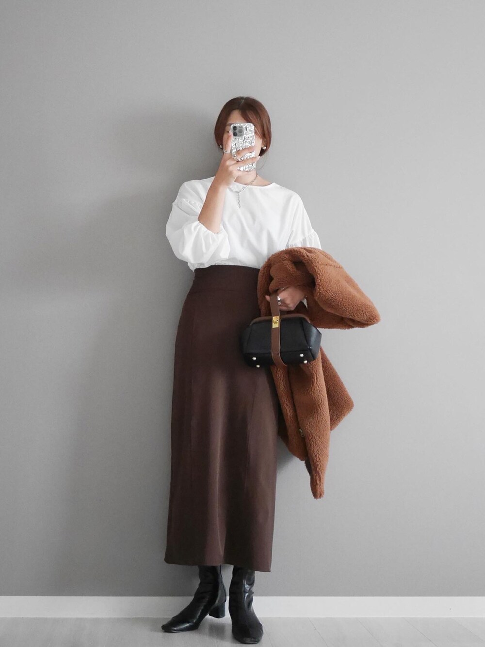ブラウン系のベスト、ブラウン系のスカート、ブラック系のショルダーバッグを着用したレディースの秋コーディネートの2枚目の写真