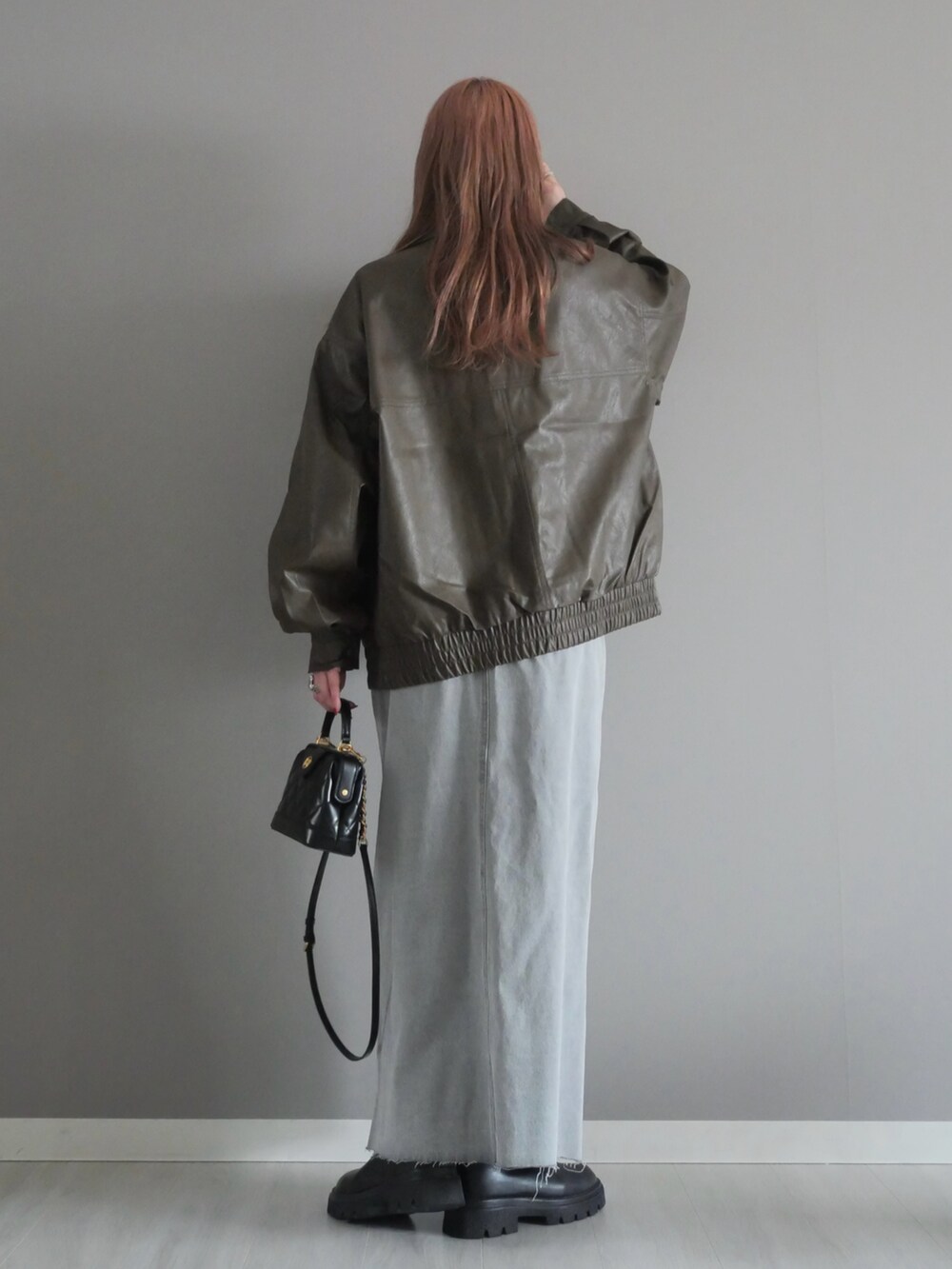 グレー系のデニムスカート、ブラック系のトートバッグ、ブラウン系のブルゾンを着用したレディースの冬コーディネートの5枚目の写真