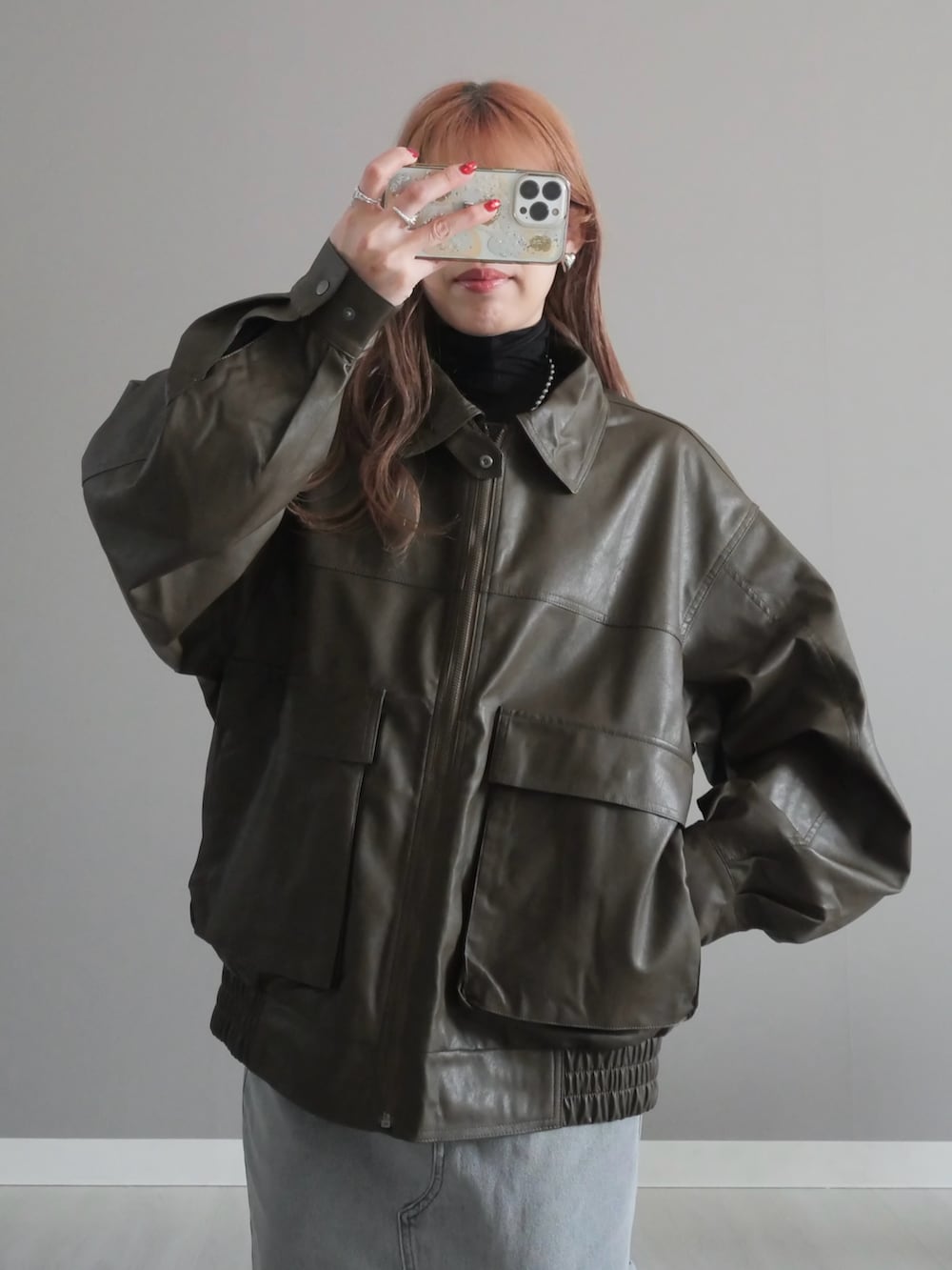 グレー系のデニムスカート、ブラック系のトートバッグ、ブラウン系のブルゾンを着用したレディースの冬コーディネートの3枚目の写真