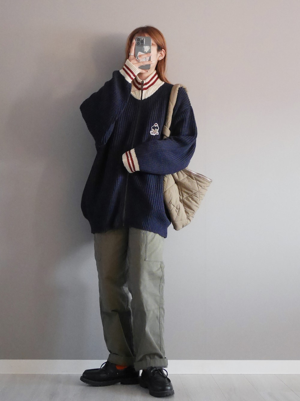 ブルー系のニット/セーター、グリーン系のパンツ、ブラウン系のメッセンジャーバッグを着用したレディースの秋コーディネートの2枚目の写真