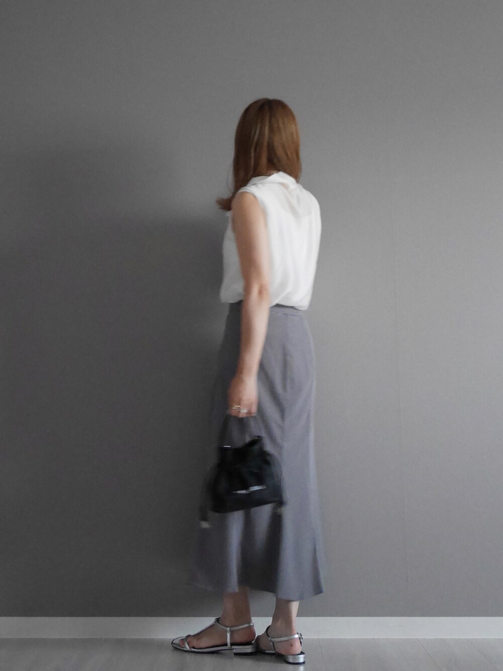 グレー系のスカート、ホワイト系のTシャツ/カットソー、ブラック系のバッグを着用したレディースの夏コーディネートの2枚目の写真