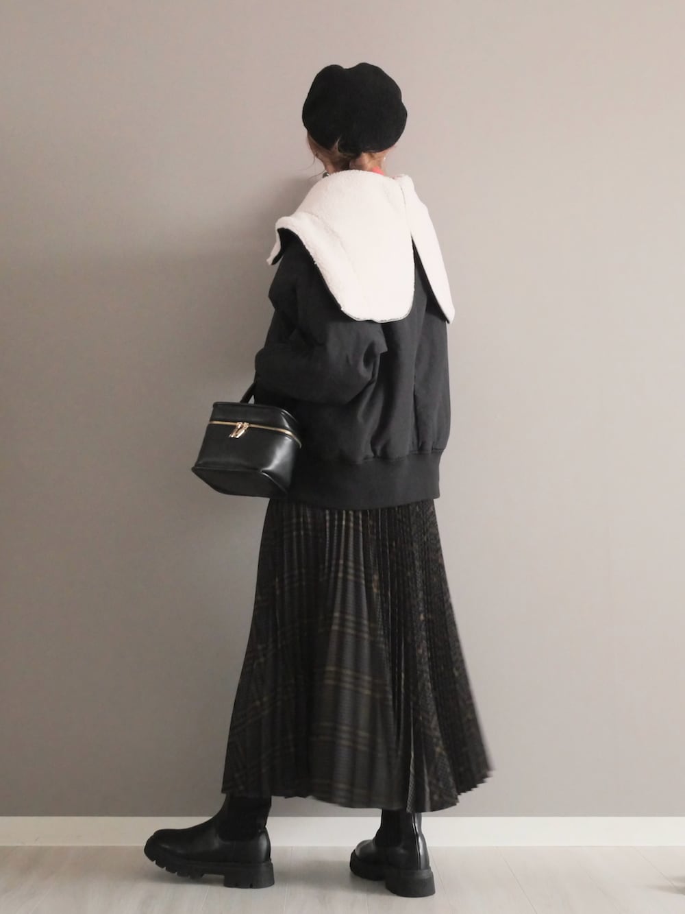 ブラック系のブルゾン、グレー系のスカート、ブラック系のショルダーバッグを着用したレディースの秋コーディネートの3枚目の写真