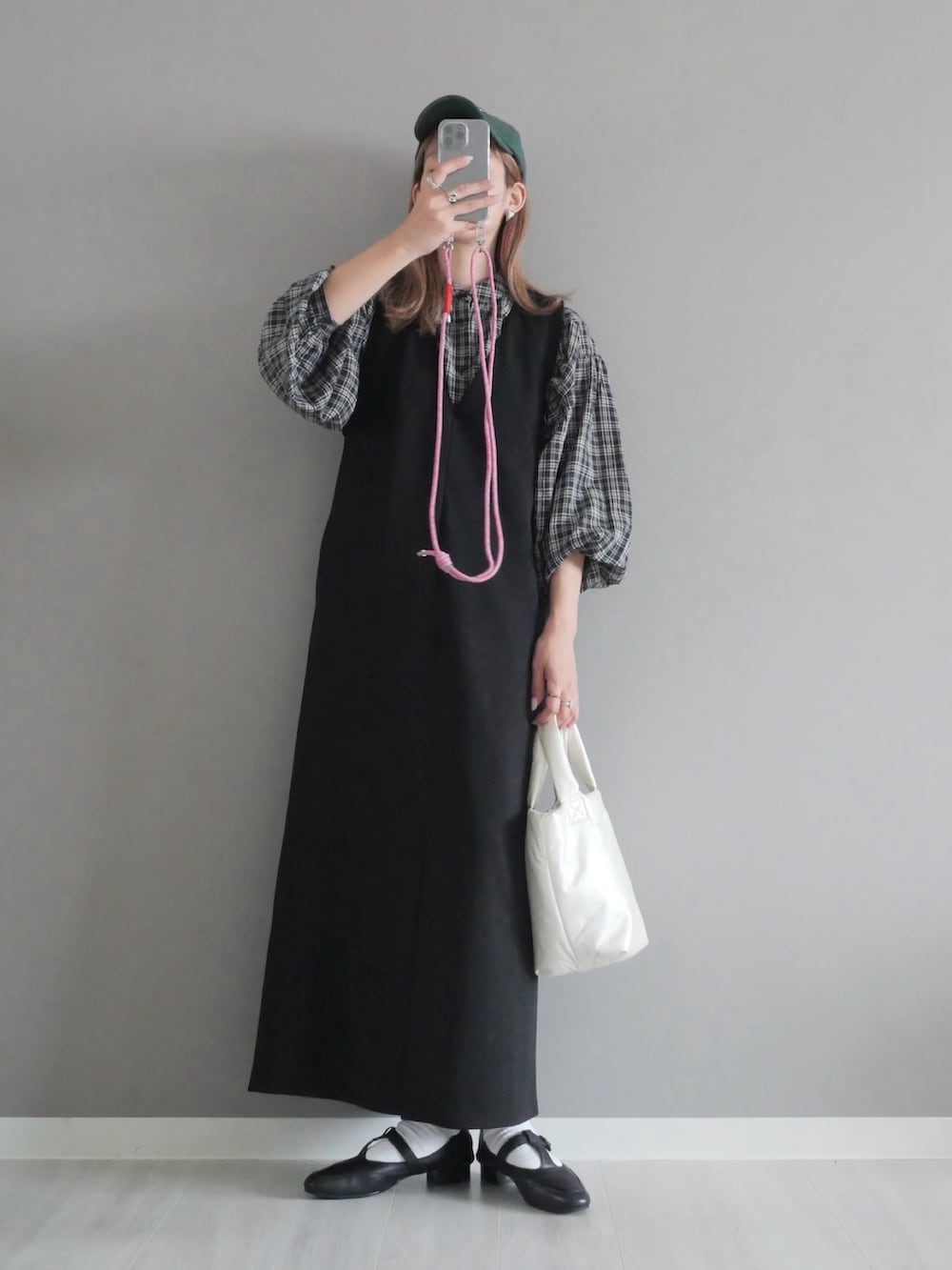 ブラック系のジャンパースカート、ホワイト系のハンドバッグ、ブラック系のパンプスを着用したレディースの秋コーディネートの2枚目の写真