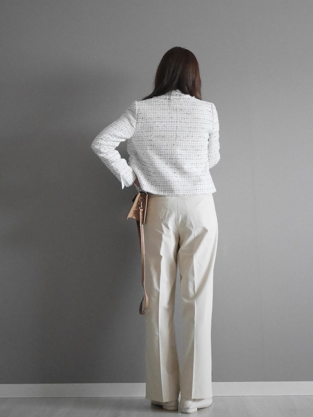 ブルー系のノーカラージャケット、ホワイト系のパンツ、ベージュ系のショルダーバッグを着用したレディースの冬コーディネートの2枚目の写真