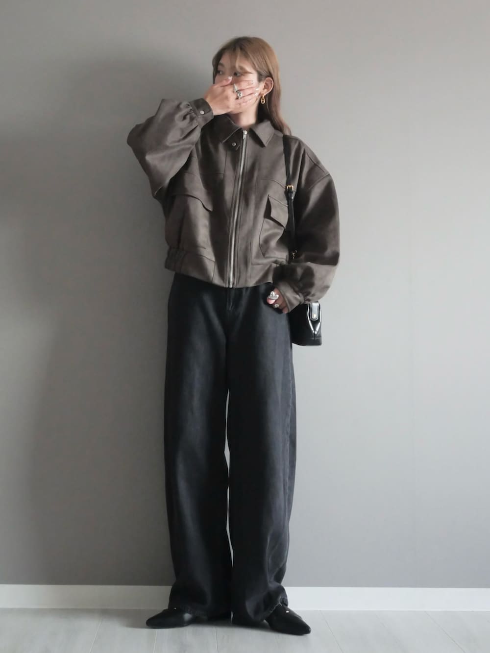 ブラウン系のブルゾン、ブラック系のトートバッグ、ブラック系のパンプスを着用したレディースの秋コーディネートの2枚目の写真