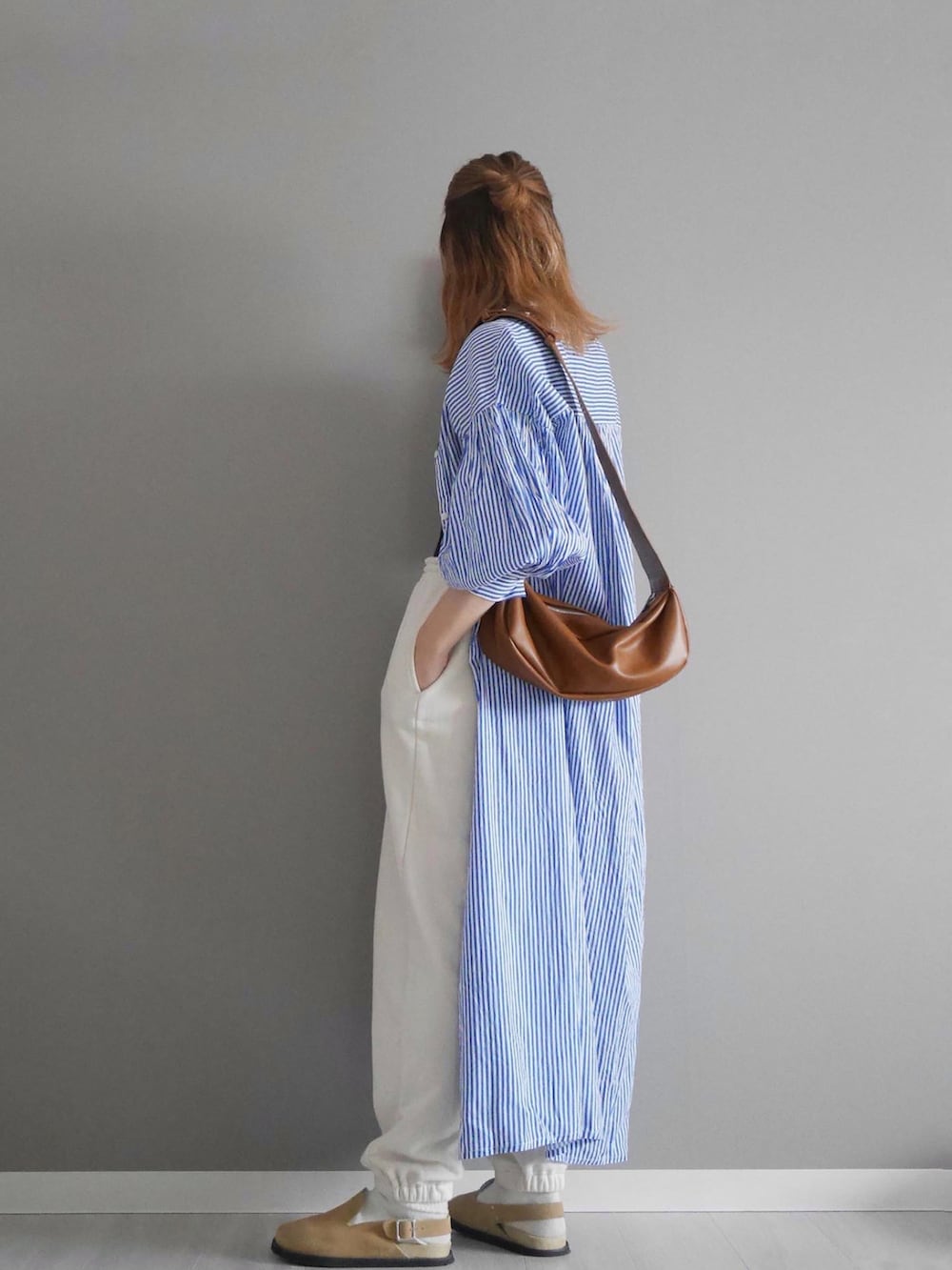 ブルー系のシャツワンピース、ホワイト系のパンツ、イエロー系のショルダーバッグを着用したレディースの春コーディネートの2枚目の写真